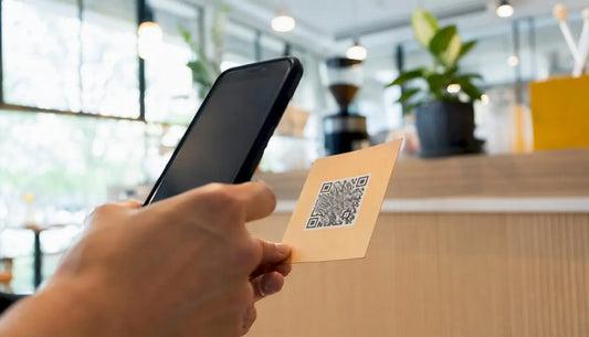 Eine Hand hält ein Smartphone und scannt damit einen QR-Code.