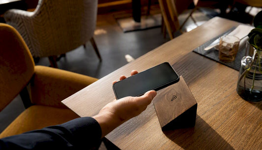 Eine Hand hält das Smartphone an einen NFC-Bewertungsstand und gibt direkt vor Ort eine Bewertung ab.