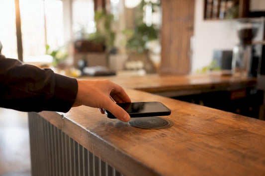Eine Hand hält ein Smartphone und tippt es auf ein NFC-Tag.