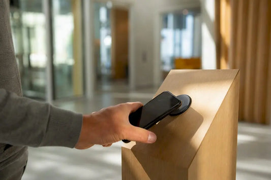 Hand mit Smartphone tippt auf NFC-Tag im Café