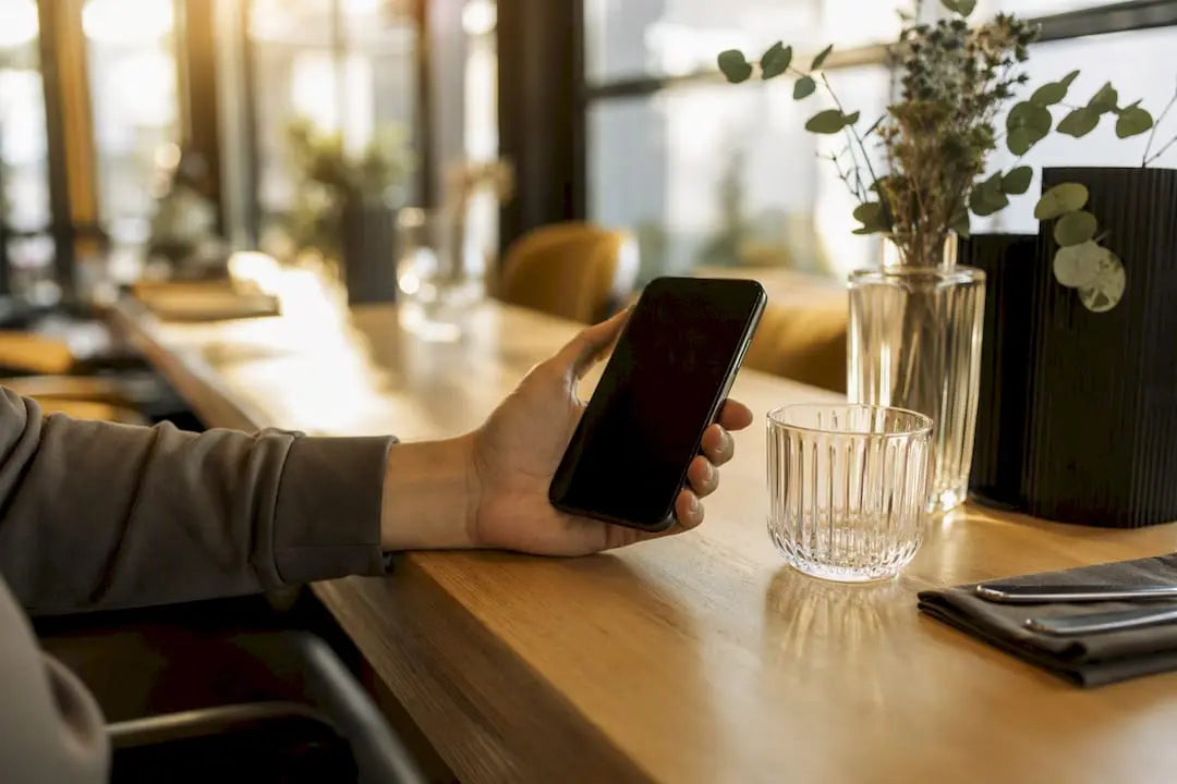 Hand, die ein Smartphone über einem Tresen hält