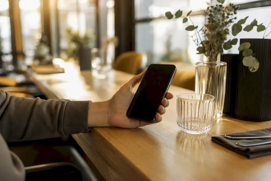 Hand, die ein Smartphone über einem Tresen hält